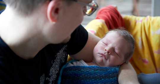 Männliche Person hält schlafenden Säugling im Arm